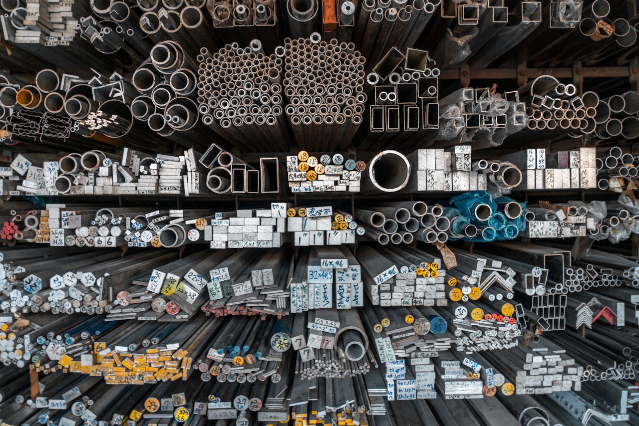 services-01 A detailed assortment of metal bars, tubes, and pipes stored on shelves in an industrial setting.