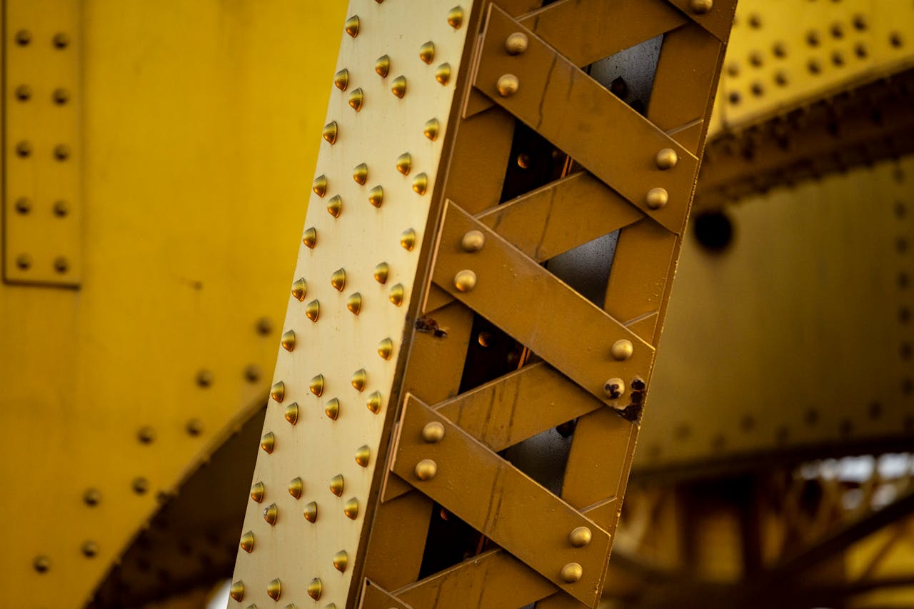 services-04 Detailed close-up of a yellow metal structure showcasing rivets and beams in an industrial setting.