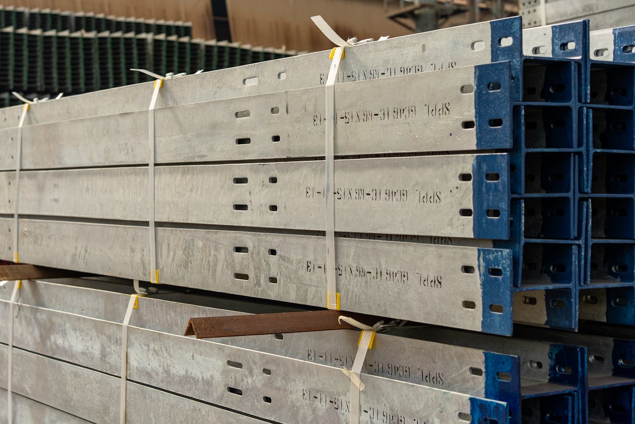 services-bg Close-up of stacked metal beams secured with straps in an industrial warehouse setting.