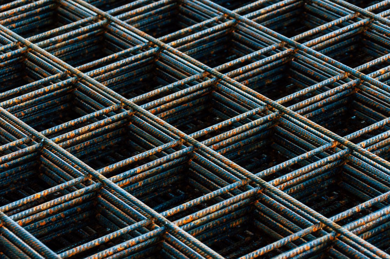 our-story Detailed view of a rusty rebar grid used in construction work, showing texture and pattern.