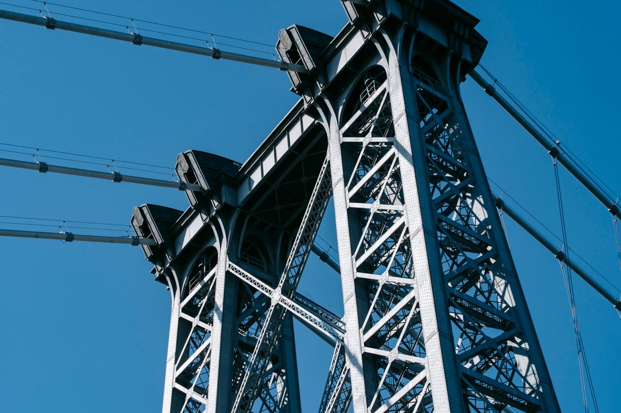 services-02 From below of suspension Williamsburg Bridge with long metal constructions against cloudless sky